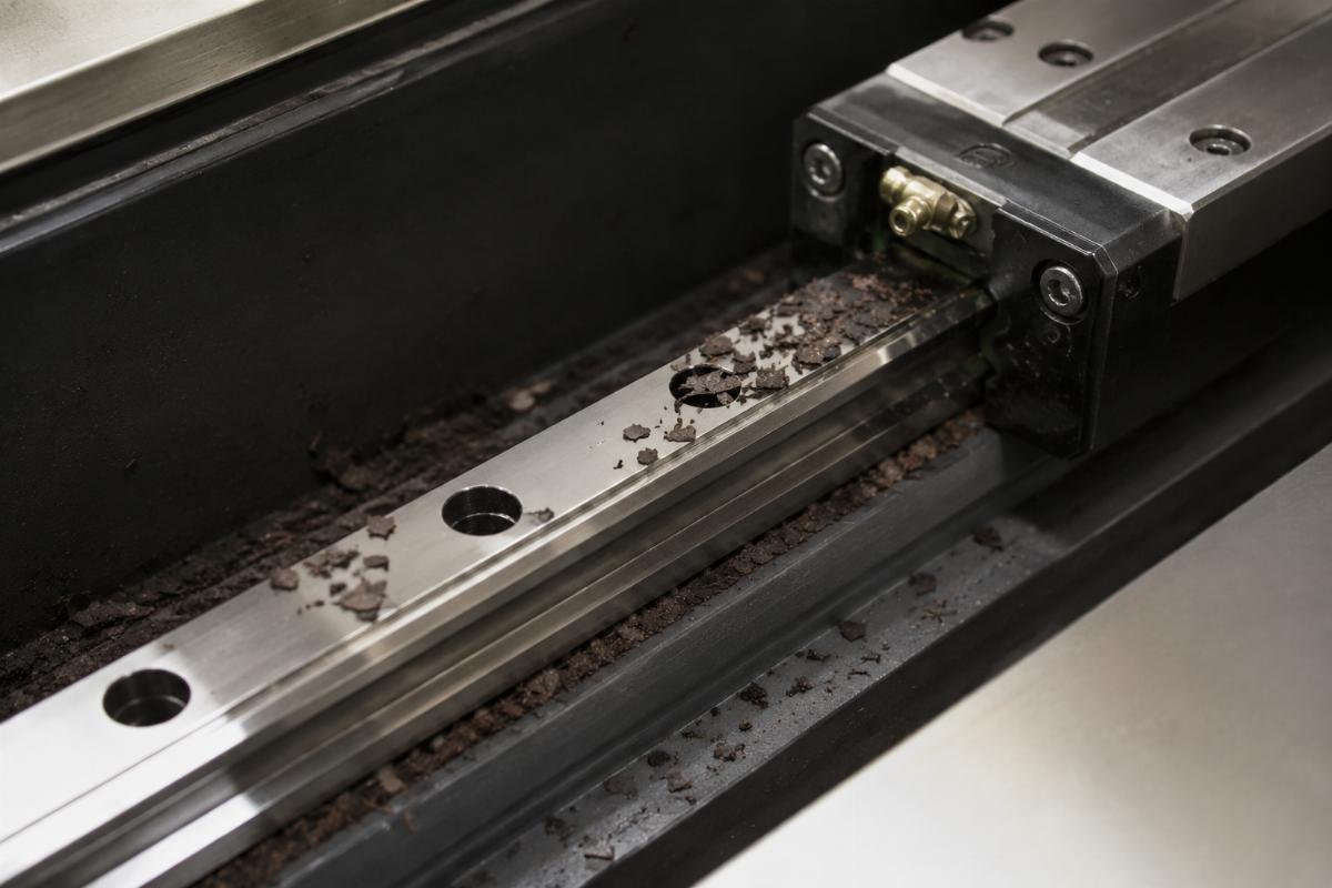 Close-up of leather debris on linear guide rail Guide rail debris accumulation on cutting machine
